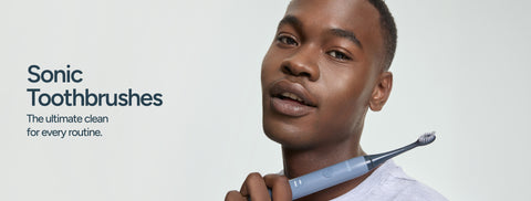 Man holding a toothbrush against a grey background with text that says "Sonic Toothbrushes, The ultimate clean for every routine".